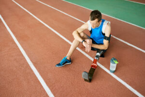Amputee athlete with artificial leg sitting on running track in a stadium