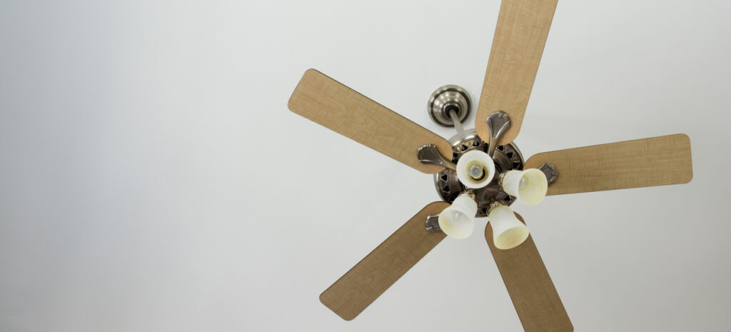 A ceiling fan with wooden panels and a light fixture build in against a white ceiling.